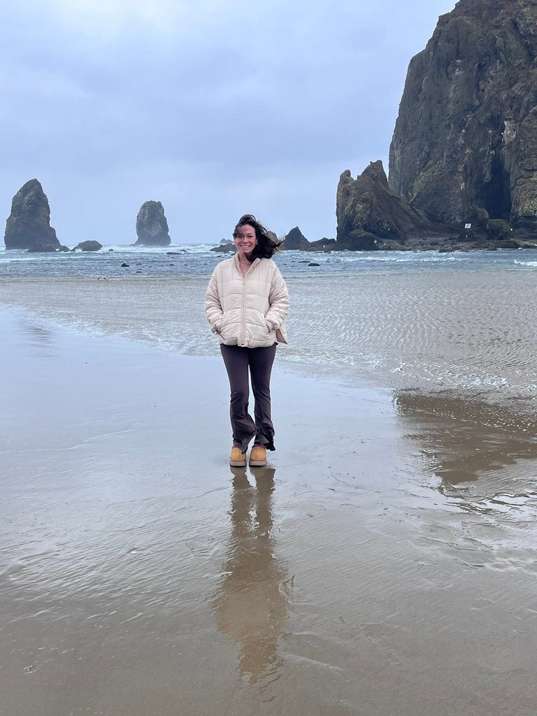 Crystal standing in front of Haystack Rock at Cannon Beach on the Oregon Coast.